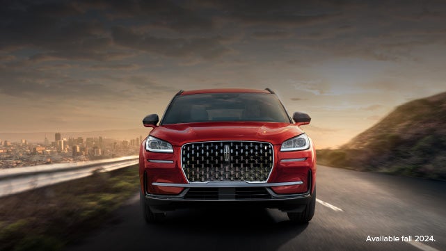 A 2025 red Lincoln Corsair® SUV is being driven down a road at sunset. | Wallace Lincoln in Fort Pierce FL