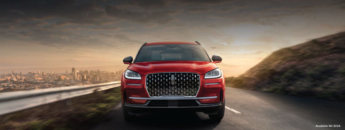 A 2025 red Lincoln Corsair® SUV is being driven down a road at sunset. | Wallace Lincoln in Fort Pierce FL