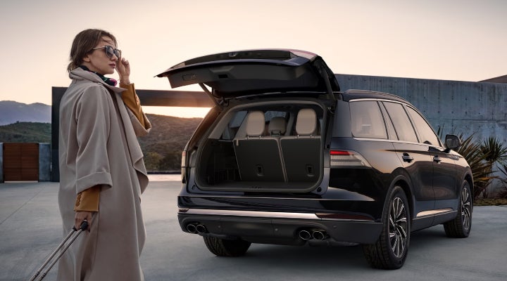 A woman approaches a 2026 Lincoln Aviator® SUV with its rear liftgate open. | Wallace Lincoln in Fort Pierce FL