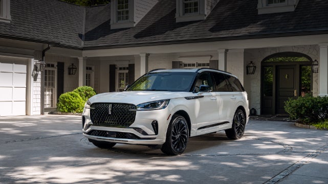 A white 2026 Lincoln Aviator® SUV is parked in the driveway of a luxury home. | Wallace Lincoln in Fort Pierce FL