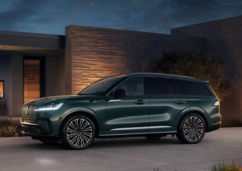 A green 2027 Lincoln Aviator® SUV is parked outside a contemporary home. | Wallace Lincoln in Fort Pierce FL