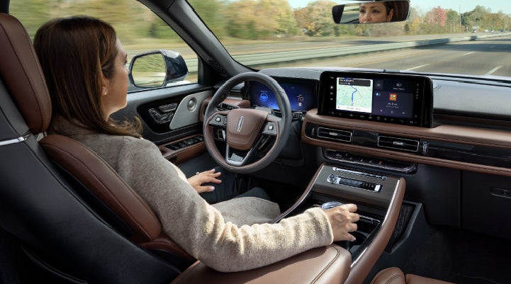 A 2027 Lincoln Aviator® SUV is being driven hands-free on a highway lined with trees. | Wallace Lincoln in Fort Pierce FL