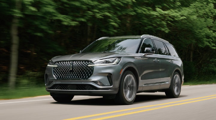 A 2027 Lincoln Aviator® SUV is being driven down a road lined with trees. | Wallace Lincoln in Fort Pierce FL