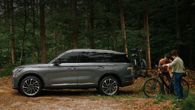 A father and son load e-bikes on a bike rack attached to a 2027 Lincoln Aviator® SUV. | Wallace Lincoln in Fort Pierce FL